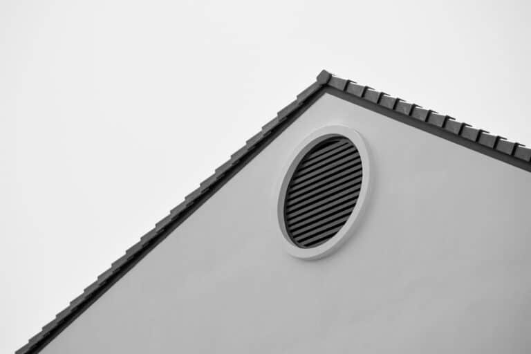 Stainless steel spinning turbine roof vent mounted on a terracotta tile roof under a bright blue sky